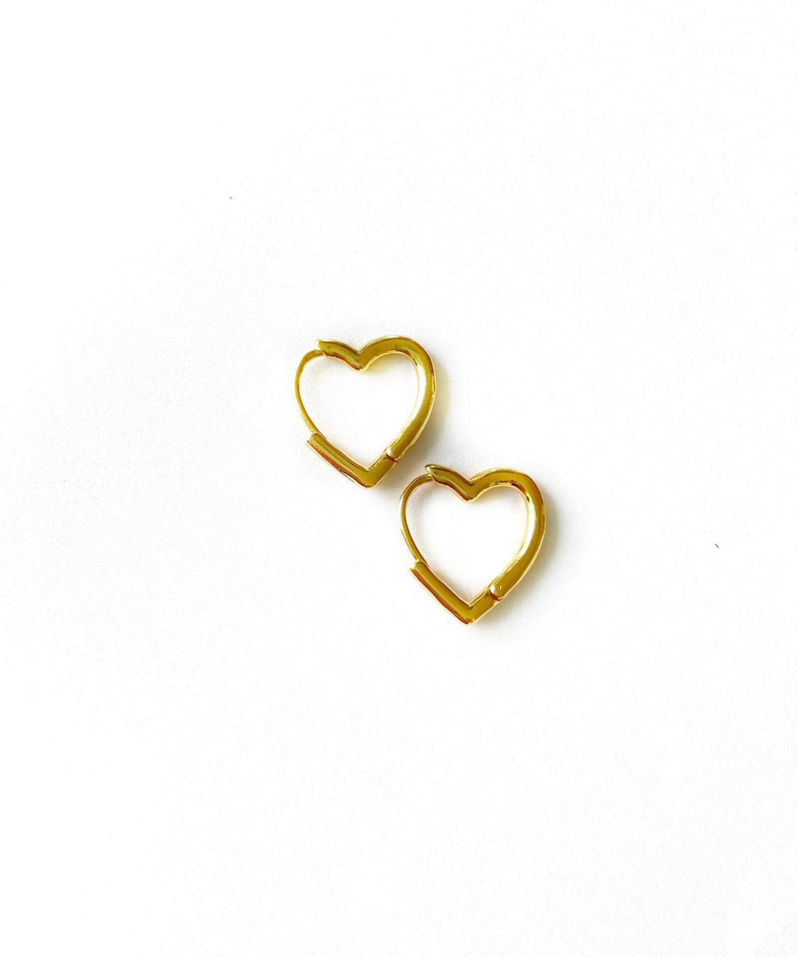 small and dainty open heart shaped huggie earrings in a gold finish over italian brass